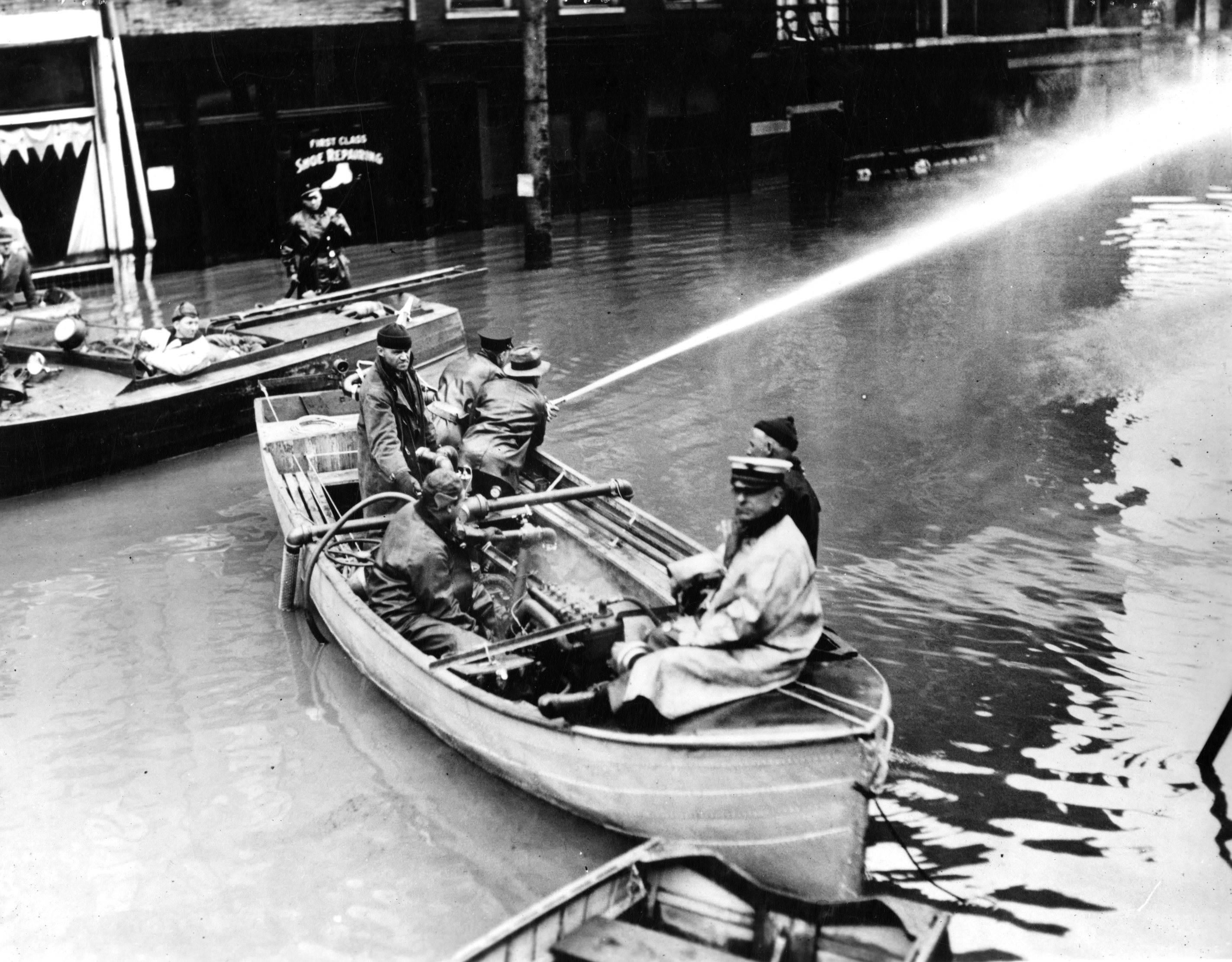 7.	Coast Guardsmen rig a watercraft as a fireboat by pumping floodwater to feed their firehose fighting a conflagration in downtown Cincinnati. (U.S. Coast Guard)