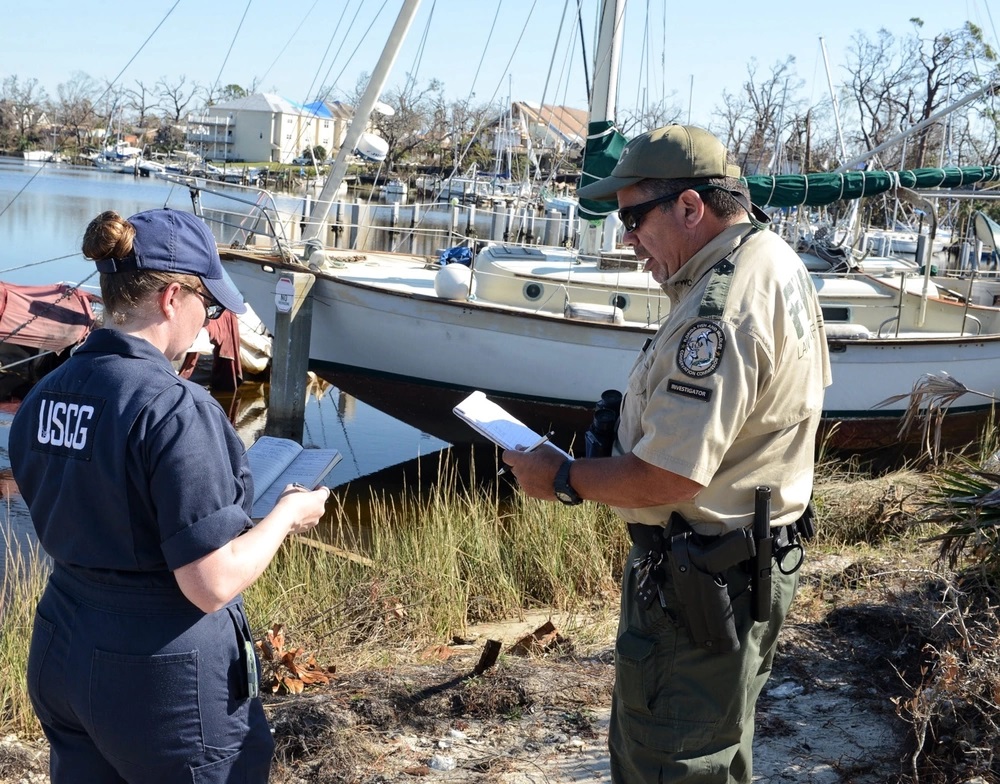 Coast Guard Petty Officer 2nd Class Valerie Van Tine and Florida Fish and Wildlife Conservation Commission Investigator David Terrones assess vessels for damage and possible pollution in Massalina Bayou, Panama City, Fla., Oct. 31, 2018. The Emergency Support Function-10 Unified Command, made up of the U.S. Coast Guard and the FWC, are collaborating to tackle pollution threats in areas affected by Hurricane Michael. U.S. Coast Guard photo by Chief Petty Officer Gail Dale.