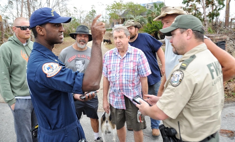 Coast Guard Petty Officer 2nd Class TJ James and Florida Fish and Wildlife Conservation Commission Investigative Lieutenant James Holcomb address vessel removal questions from residents of Cooks Bayou in Panama City, Fla., Nov. 2, 2018. The Emergency Support Function-10 Unified Command, made up of the U.S. Coast Guard and the FWC, are collaborating to tackle pollution threats in areas affected by Hurricane Michael. U.S. Coast Guard photo by Petty Officer 2nd Class Paul Dragin.