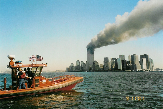 Deployed Coast Guard rigid-hull inflatable boat with World Trade Center burning in background. (U.S. Coast Guard)