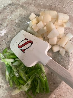 Senior Chief Petty Officer Adam Shelton preps the scallions and pears for his contribution to the 2022 MyCG Holiday Menu, Roasted Brussels Sprouts with Pear, Nuts, and Scallions, Washington, D.C., Dec. 9, 2022. (Photo courtesy of Senior Chief Petty Officer Shelton)