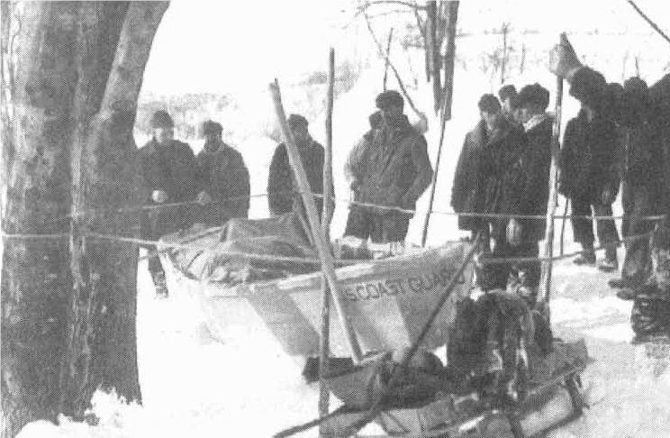 A photograph of the rescue party on the beach standing next to BM2 Earl Cunningham’s rescue skiff. (Joint Archives of Holland, Michigan)