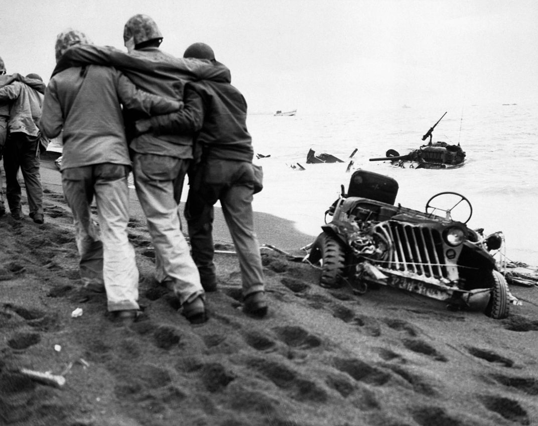 Wounded marines evacuated from the beachhead to aid stations among demolished tanks and military vehicles. (National Archives)