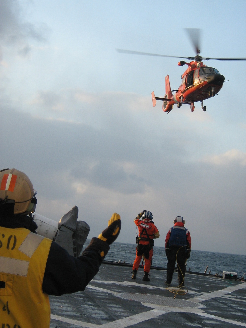 . Munro’s HH-65 Dolphin helicopter depositing Alaska Ranger survivors on the flight deck of the Munro. (Ensign Daniel Schrader, U.S. Coast Guard)