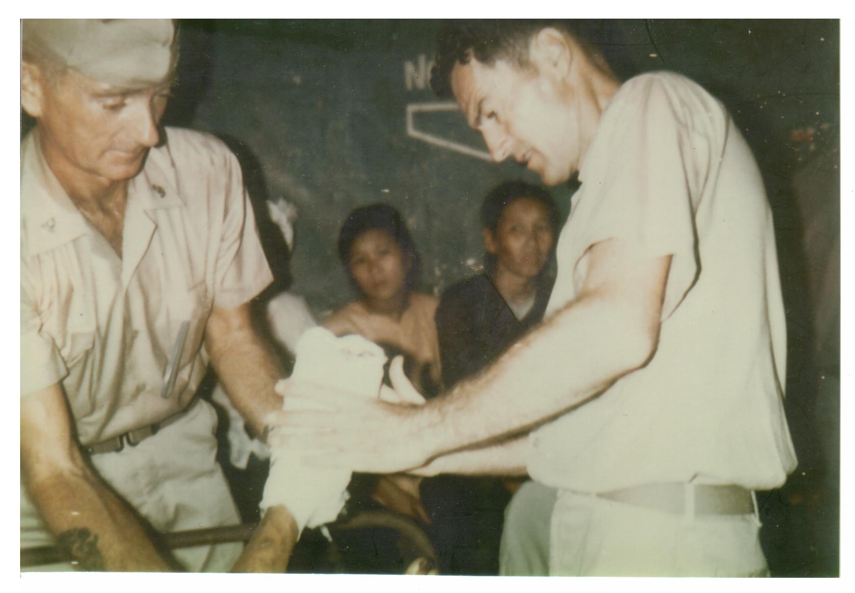 Doc White providing medical care to wounded Vietnamese villagers. (Mrs. Misa White)