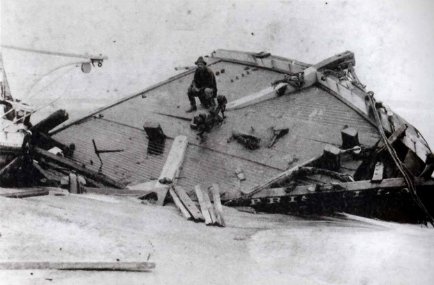 Surfman Rasmus Midgett seated on the beached bow section of the Priscilla after the storm had passed. (National Park Service)