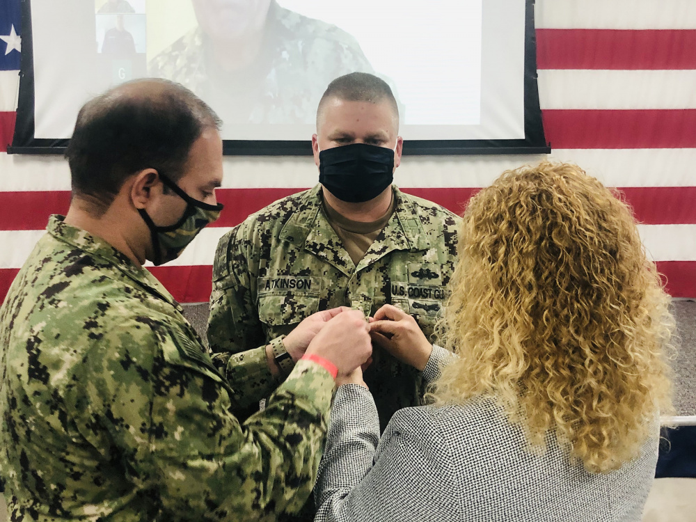 Megan Atkinson pins a rank insignia Dec. 12, 2020, on Petty Officer 2nd Class Trevor Atkinson of Winter Haven, Florida, during a virtual meritorious advancement ceremony at Coast Guard Port Security Unit 307 in Clearwater, Florida. Atkinson, is a tactical boat crewman at PSU 307 and became the second Coast Guard reservist to be meritoriously advanced under a new program established by the commandant in March 2020. Coast Guard photo courtesy of Lt. Glenn Sanchez