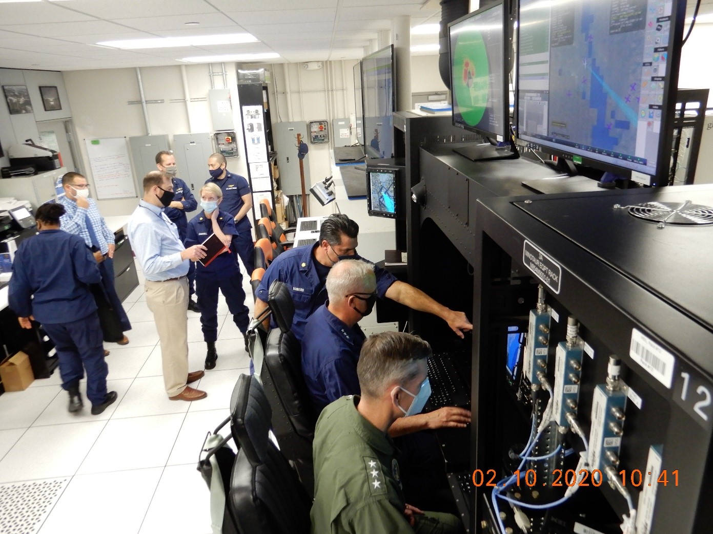 Deputy Commandant of Operations (DCO) Vice Adm. Scott Buschman (middle) and commander Naval Air Systems Command (NAVAIR) at U. S. Coast Guard Minotaur Mission System Integration Laboratory (MSIL) at Naval Air Station (NAS) Patuxent River (PAX), Maryland.