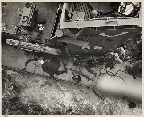 3.	Coast Guardsmen swing an Army truck overside as their combat transport lies off a bridgehead established by the Americans as Paesternum, just south of Salerno. Coast Guardsmen waiting in a landing barge alongside the transport will take the truck ashore. (NARA)