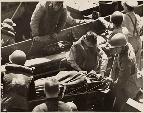 6.	A Coast Guard pharmacist’s mate gives first aid to an American fighter who has just returned from the liberation beach. The wounded man is transferred from a landing boat to a Coast Guard assault transport off the coast of France. (NARA)