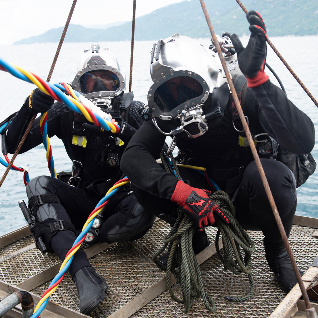 U.S. Coast Guard DV2 Dakota Gasdiel-Goldberg, second class diver with the Regional Dive Locker West, left, and U.S. Army Spc. Thomas Pagano, second class diver with the 7th Engineer Dive Detachment, descend to the underwater units on a salvage basket during recovery operations off the coast of Nha Trang, Khánh Hòa Province, Vietnam, May 25, 2023.  Multiple dive, recovery and possible identification techniques are used during the recovery mission to account for variables, both above and below surface.  Service members from the U.S. Army 7th Engineer Dive Detachment and the U.S. Coast Guard Regional Dive Locker West combined skillsets and techniques with DPAA and one of its underwater archaeologists to take on the unique underwater recovery mission. They searched for six of the remaining 1,244 Americans unaccounted for in Vietnam over a span of 75 plus days. (U.S. Marine Corps photo by Sgt. Morgan L. R. Burgess)